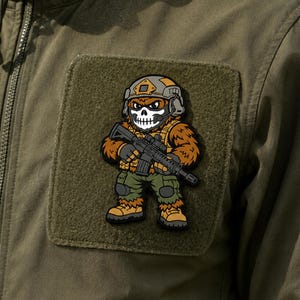 May include: A rectangular olive green hook-and-loop patch featuring a cartoon character wearing a tactical helmet, a skull mask, and military gear. The character is holding a black rifle and is dressed in brown fur, green pants, and tan boots.
