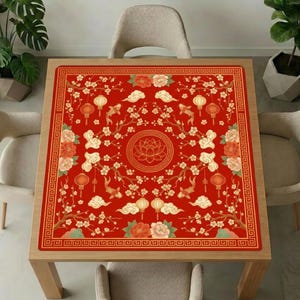 Red lantern koi lotus mahjong mat covering a square wooden dining table, surrounded by neutral upholstered chairs and green indoor plants.