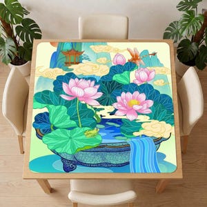 Lotus pond mahjong table mat covering a square wooden table with four cream chairs in a bright room decorated with green potted plants.