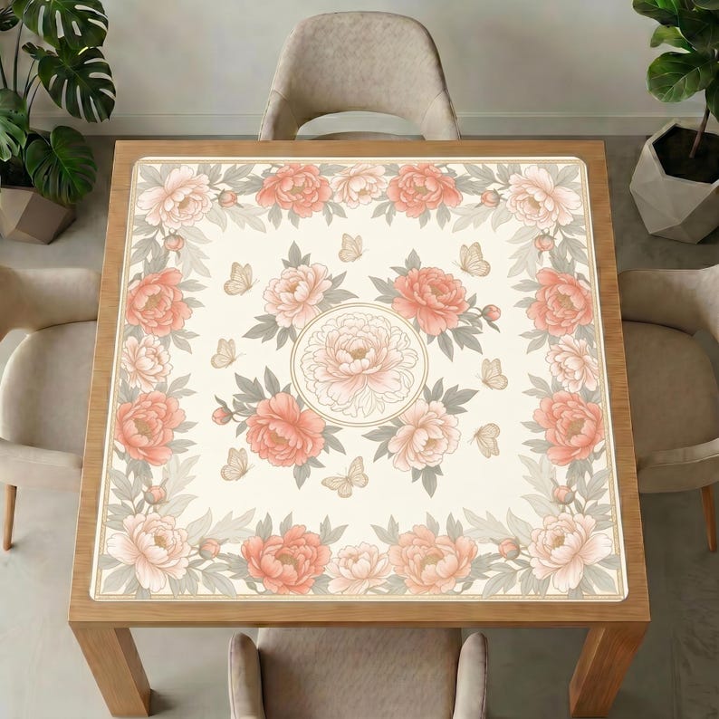 Peony mahjong table mat laid on a square wooden table, surrounded by beige upholstered chairs and green indoor plants.