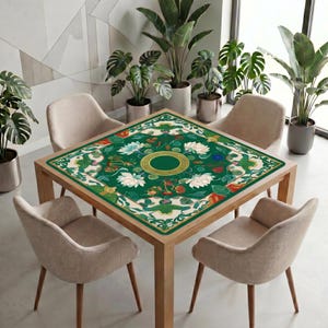 Green lotus mahjong table mat covering a square wooden table with four beige chairs in a bright modern room with tall green plants.