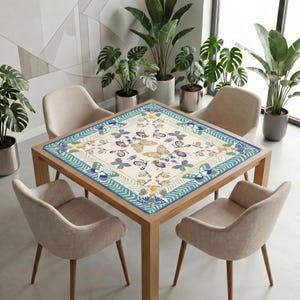Modern dining area with neutral chairs and many green plants, featuring a wooden table covered by the teal border butterfly mahjong table mat as a decorative centerpiece.