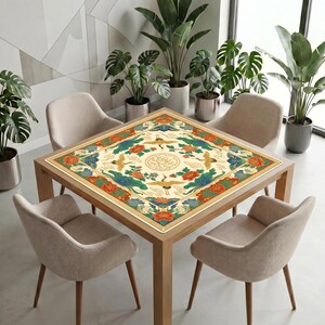 Modern dining space with many green plants and neutral chairs, featuring a wooden table covered by the colorful crane lotus mahjong table mat as a decorative centerpiece.