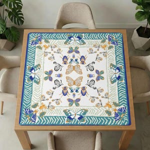 Wooden dining table with beige chairs and plants, topped with the teal border butterfly mahjong table mat covering the whole tabletop.