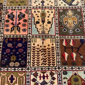 Pu&ograve; includere: Un tappeto rettangolare caratterizzato da una griglia di pannelli distinti, ognuno contenente motivi geometrici e floreali unici nei toni del rosa, verde oliva, marrone, blu navy e crema. Il bordo presenta un motivo a frecce ripetuto.