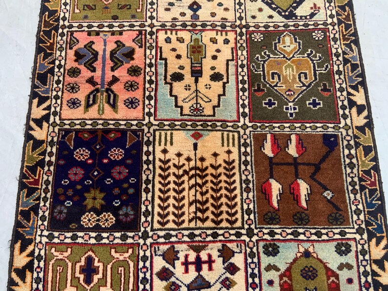 Pu&ograve; includere: Un tappeto rettangolare caratterizzato da una griglia di pannelli distinti, ognuno contenente motivi geometrici e floreali unici nei toni del rosa, verde oliva, marrone, blu navy e crema. Il bordo presenta un motivo a frecce ripetuto.