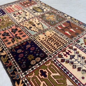 Antique tribal wool rug, 4'9" x 2'10", hand-knotted garden panel design with 15 compartments featuring stylized birds, florals, trees, and geometric medallions in navy blue, cream, olive green, pink, and brick red. Vintage one-of-a-kind wool pile rug on cotton foundation, black and cream serrated-leaf border with dotted diamond guard stripe. Small accent rug ideal for an entryway, hallway, or bathroom. Handwoven boho tribal area rug.
