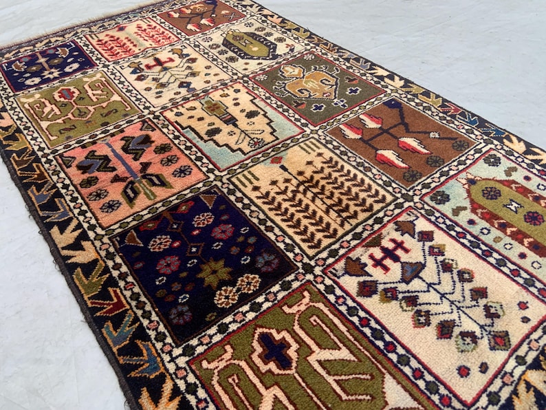 Antique tribal wool rug, 4'9" x 2'10", hand-knotted garden panel design with 15 compartments featuring stylized birds, florals, trees, and geometric medallions in navy blue, cream, olive green, pink, and brick red. Vintage one-of-a-kind wool pile rug on cotton foundation, black and cream serrated-leaf border with dotted diamond guard stripe. Small accent rug ideal for an entryway, hallway, or bathroom. Handwoven boho tribal area rug.