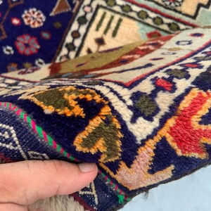 Pu&ograve; includere: Un tappeto in lana annodato a mano con un campo blu profondo e intricati motivi floreali e geometrici in rosso, arancione, verde e crema. Il bordo presenta un design complesso con motivi ripetitivi, un pelo spesso e una trama densa.
