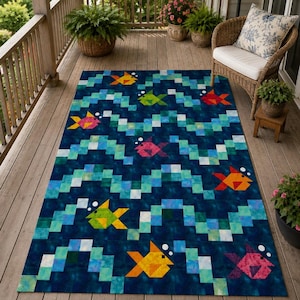 May include: A rectangular area rug featuring a dark blue background with a repeating pattern of light blue and white pixelated zigzag waves. The design includes multiple colorful fish in shades of yellow, green, orange, and pink with white bubbles.