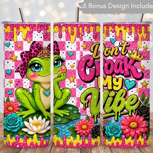 May include: A cylindrical tumbler featuring a green frog with a pink leopard print bow and crown, sitting on a lily pad. The design includes a pink and white checkered background, yellow dripping paint, flowers, and the text Don't Croak My Vibe.