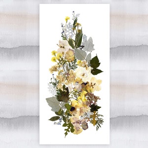 May include: A pressed flower arrangement featuring a variety of yellow and white flowers, including roses, daisies, and other wildflowers. The flowers are arranged in a vertical bouquet on a white background.