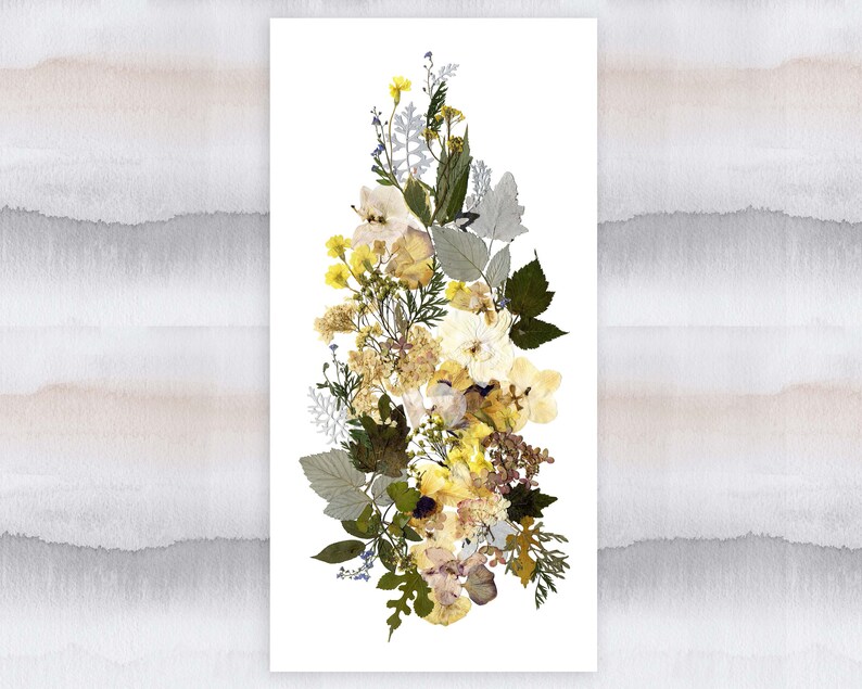 May include: A pressed flower arrangement featuring a variety of yellow and white flowers, including roses, daisies, and other wildflowers. The flowers are arranged in a vertical bouquet on a white background.