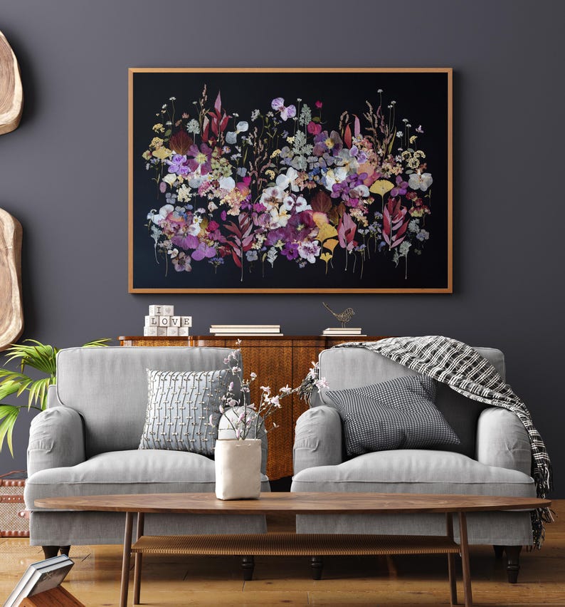 K&ouml;nnte beinhalten: Ein rechteckiges Wandbild mit einer dichten Anordnung gepresster Blumen und Bl&auml;tter in Violett-, Rosa-, Gelb- und Gr&uuml;nt&ouml;nen vor einem einfarbigen schwarzen Hintergrund, eingefasst in einen d&uuml;nnen, hellen Holzrahmen.