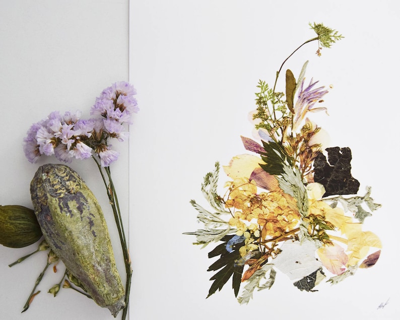 May include: A pressed flower arrangement with a variety of dried flowers and leaves in shades of yellow, green, and purple. The flowers are arranged in a loose, organic style, and the overall effect is one of natural beauty.