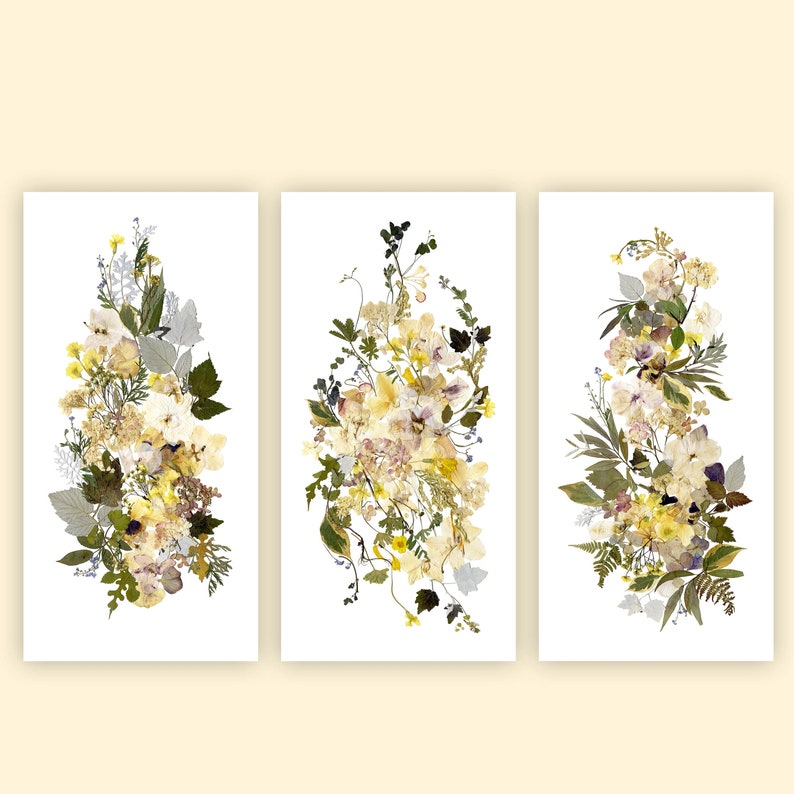 May include: Three framed botanical prints featuring pressed flowers in shades of yellow, white, and green. The flowers are arranged in a vertical bouquet shape.