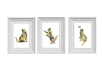 May include: Three white picture frames with a floral cat design in each. The cat in the left frame is sitting, the cat in the middle frame is jumping, and the cat in the right frame is looking up at a butterfly.