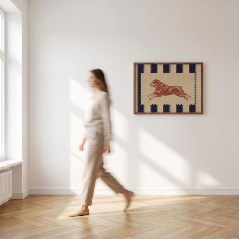 Puede incluir: Una l&aacute;mina de arte mural rectangular en un marco de madera que presenta una ilustraci&oacute;n roja de un perro corriendo sobre un fondo beige con un borde festoneado y rayas verticales azul marino en los bordes superior e inferior.