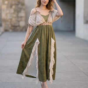May include: A floor-length olive green dress featuring a sweetheart neckline, off-the-shoulder puff sleeves with tie details, and a fitted bodice with a patterned waistband. The skirt includes vertical cream-colored ruffled panels and a subtle floral print.