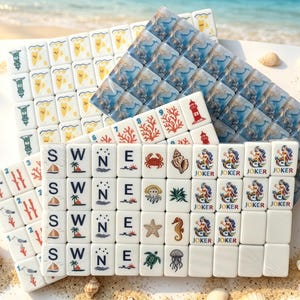 K&ouml;nnte beinhalten: Ein Set wei&szlig;er Mahjong-Spielsteine mit nautischen Motiven und Strandthemen, darunter Leuchtt&uuml;rme, Korallen, Krabben, Seesterne, Meeresschildkr&ouml;ten, Quallen und als Joker gekennzeichnete Meerjungfrauen sowie Spielsteine mit S, W, N, E und Segelbooten.