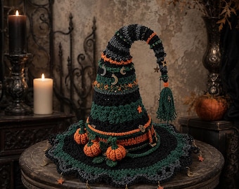 May include: A crocheted witch hat featuring horizontal stripes in black, dark green, and orange. The hat is adorned with small orange pumpkins at the base, metal moon and star charms, and a green tassel hanging from the curved, pointed tip.