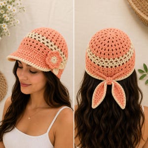 May include: A peach and cream crochet hat featuring a short brim, a decorative flower accent on the side, and a tie closure at the back. The hat is constructed with an openwork stitch pattern in alternating bands of peach and cream yarn colours.
