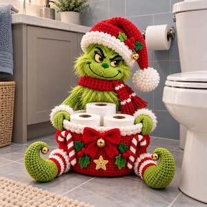 Puede incluir: Una figura del Grinch tejida a ganchillo con gorro de Papá Noel y bufanda roja y blanca, sosteniendo una cesta roja tejida que contiene tres rollos de papel higiénico. La cesta tiene un lazo rojo, una estrella dorada, acebo y bastones.