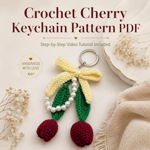 Puede incluir: Un llavero de cerezas tejido a ganchillo con dos cerezas de hilo rojo oscuro, dos hojas verdes, un lazo de hilo amarillo pálido y una hilera de perlas blancas unidas a una anilla de metal plateado. El texto dice Crochet Cherry Keychain Pattern PDF.