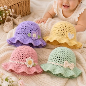 May include: Four crochet bucket hats in purple, yellow, pink, and light green. The purple hat features a flower applique, the yellow hat has a heart patch, the pink hat includes a white daisy, and the light green hat displays a small bow.