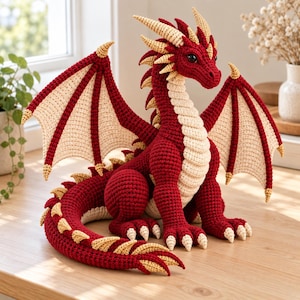 May include: A handcrafted crochet dragon toy featuring a deep red body with cream-colored underbelly, wings, and spikes. The mythical creature has large dark eyes, pointed ears, and a long tail, all constructed with detailed yarn stitching.