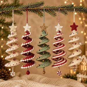 May include: Five spiral-shaped crochet Christmas tree ornaments hanging from a branch. Each tree features a star topper and unique embellishments like beads, small bells, or snowflake charms in red, white, green, and cream yarn colors.