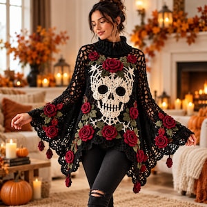 May include: A black crochet poncho featuring a large cream-colored skull motif centered on the chest, adorned with numerous three-dimensional dark red roses and green leaves. The garment has a high ribbed collar and a loose, open-knit texture.