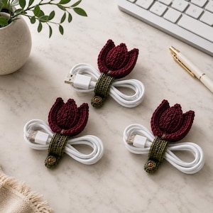 May include: Three white USB charging cables secured with crocheted cable organizers. Each organizer features a dark red tulip flower head attached to an olive green stem strap that wraps around the coiled cable and fastens with a small brown button.