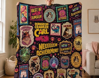 Peut inclure: Une couverture polaire noire ornée d'un collage coloré de graphismes Dungeon Crawler Carl, incluant des textes comme "Neeeeeeew Achievement!", "Best in Dungeon" et "Princess Donut", avec des illustrations de chats, un dinosaure et des potions.