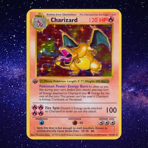 May include: A 1999 holographic Charizard trading card featuring the Stage 2 Flame Pokémon with 120 HP. The card displays the Fire Spin attack, 1st Edition stamp, and text detailing Pokémon Power: Energy Burn, length 5' 7", and weight 200 lbs.