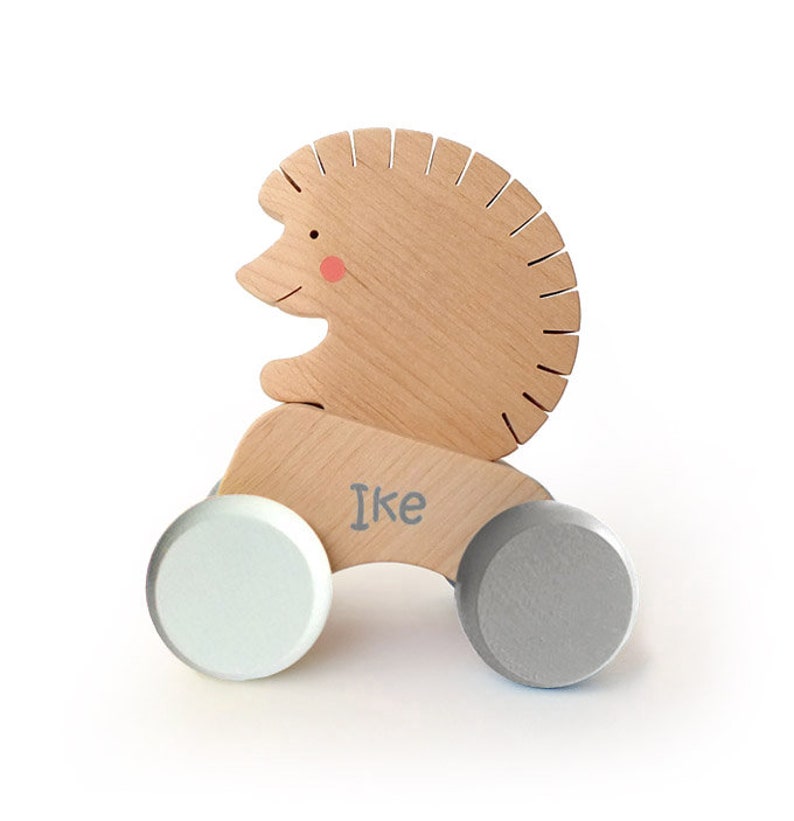 Wooden Push Toy "Hedgehog". The toy consists of two parts: a car and a removable animal. This playful, original design toy enhances active play and supports the development of motor skills.