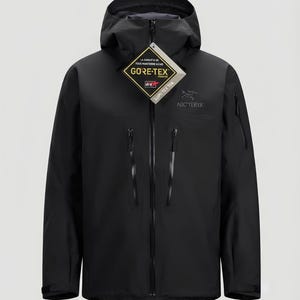 May include: A black hooded jacket featuring a full-length front zipper, two vertical chest pockets with zippers, and a small zippered pocket on the left sleeve. The Arc'teryx logo is on the chest, and a Gore-Tex tag is attached to the collar.