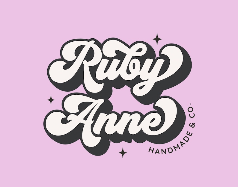 May include: A white and black logo with the text "Ruby Anne" in a retro, cursive font. The text "HANDMADE & CO." is written in a smaller font below the main text.