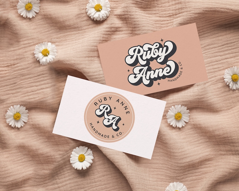 May include: Two business cards with a pink and white background. The first card features the text "Ruby Anne Handmade & Co." in a retro font. The second card features a circle with the text "Ruby Anne Handmade & Co." and the initials "RA" in a retro font.
