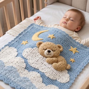 May include: A light blue crochet baby blanket featuring a three-dimensional tan teddy bear sleeping on a white cloud. The blanket is decorated with a yellow crescent moon and several yellow stars, finished with a scalloped edge border.