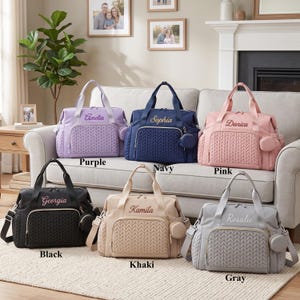 May include: Six quilted diaper bags in purple, navy, pink, black, khaki, and gray. Each bag features a front pocket with a chevron pattern, a small circular side pouch, two top handles, and a personalized name embroidered in cursive script.