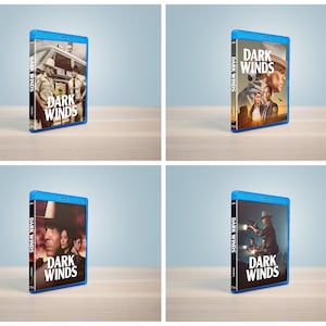 Peut inclure: Quatre boîtiers Blu-ray bleus pour la série télévisée Dark Winds, présentant chacun des illustrations différentes avec des personnages portant des chapeaux, des uniformes de police et des paysages désertiques, avec le titre Dark Winds en blanc.