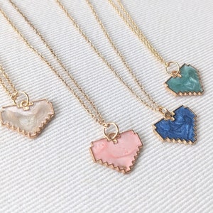 May include: Four gold necklaces with pixelated heart pendants. The hearts are in shades of pink, blue, and green.