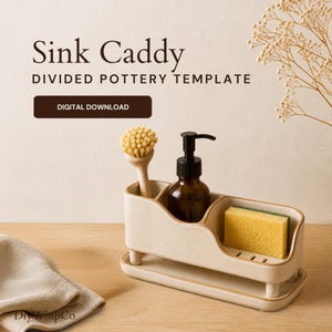 May include: A beige ceramic sink caddy with a divided interior, a matching base tray, and text that reads Sink Caddy DIVIDED POTTERY TEMPLATE DIGITAL DOWNLOAD. The caddy holds a wooden dish brush, a brown glass soap dispenser, and a yellow sponge.