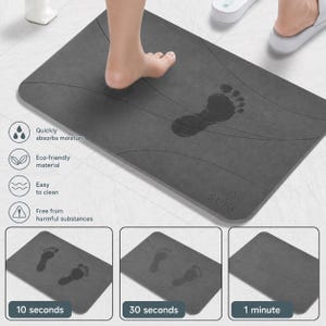 May include: A rectangular dark grey bath mat with rounded corners and curved line patterns. The surface shows a dark footprint impression that fades over time, labelled with time intervals of 10 seconds, 30 seconds, and 1 minute. Features include icons for moisture absorption, eco-friendly material, easy cleaning, and safety.