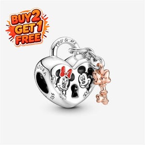 May include: A silver heart-shaped padlock charm featuring engraved images of Mickey and Minnie Mouse, with the text 'YOU & ME' and 'PANDORA S925' visible. A rose gold-toned key charm with a bow detail is attached to the top of the padlock.
