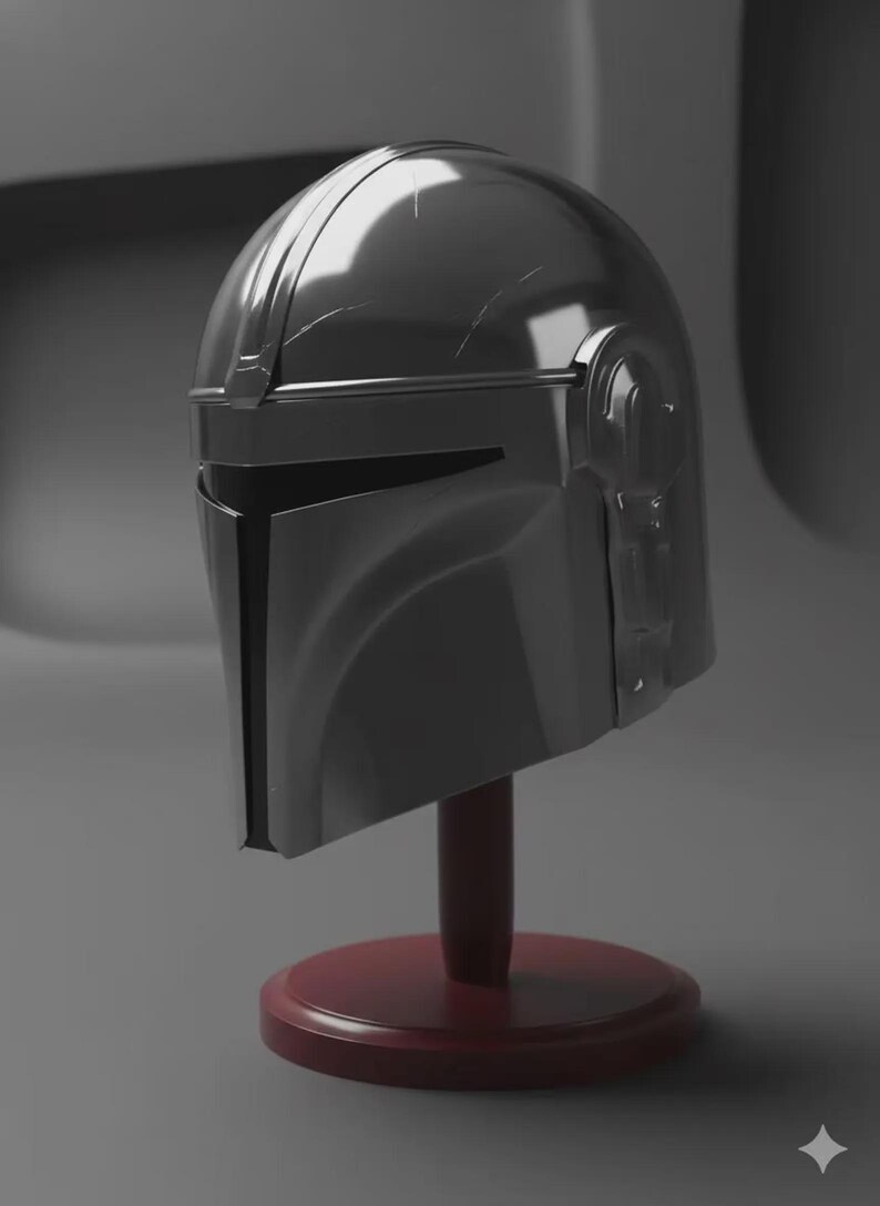 May include: A metallic silver helmet with a T-shaped visor opening, featuring a smooth, reflective surface with subtle scuff marks. The helmet is mounted on a dark red circular base with a vertical support post, displaying a sleek, curved design.