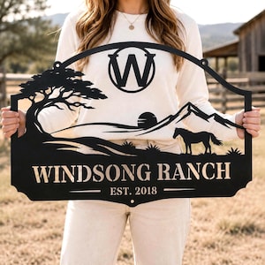 Peut inclure: Une enseigne en métal noir présentant une découpe représentant un arbre, un cheval et des montagnes sous un soleil. L'enseigne affiche la lettre W dans un cercle en haut, avec le texte WINDSONG RANCH et EST. 2018 en police sans empattement.