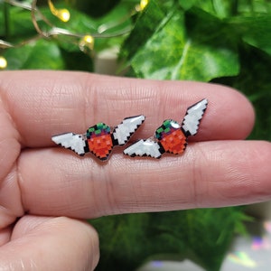Celeste strawberry with wings stud earrings.// Stainless steel, resin, plastic.