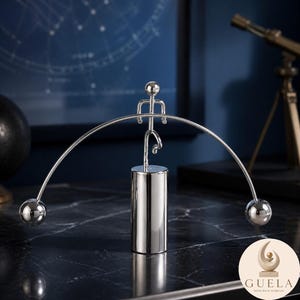 Peut inclure: Une sculpture cinétique en métal argenté représentant une silhouette stylisée en équilibre sur une base cylindrique centrale. La silhouette tient une longue tige incurvée avec une sphère polie à chaque extrémité, créant un design symétrique.